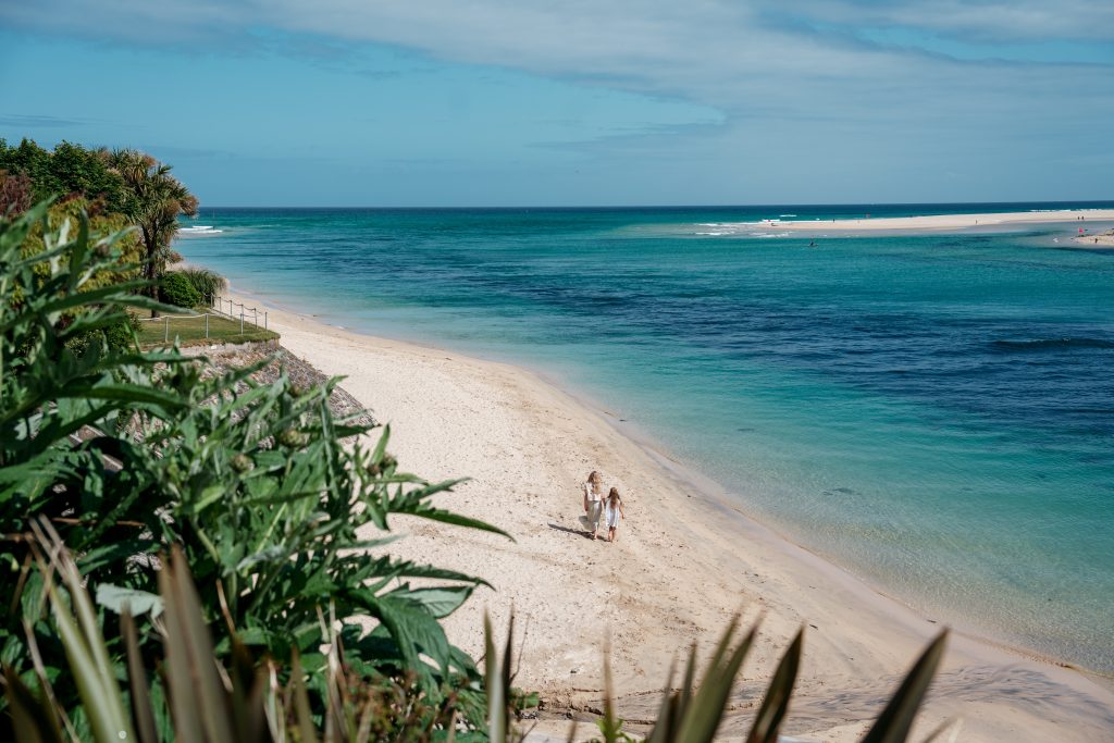 Two People on a Beach Walk on golden sand with blue seas and blue skies